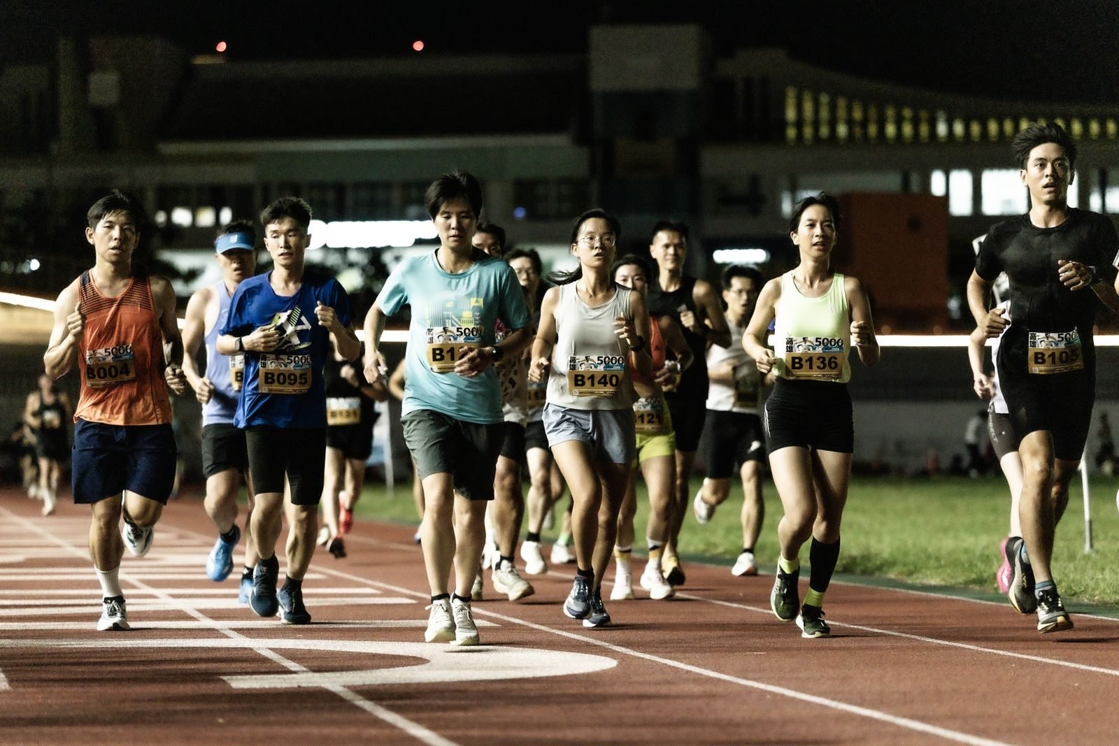 Group of runners in a night race on an athletics track