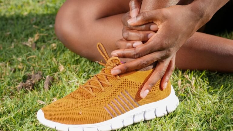 Athlete holding his ankle in a running shoe because of Achilles tendinitis pain
