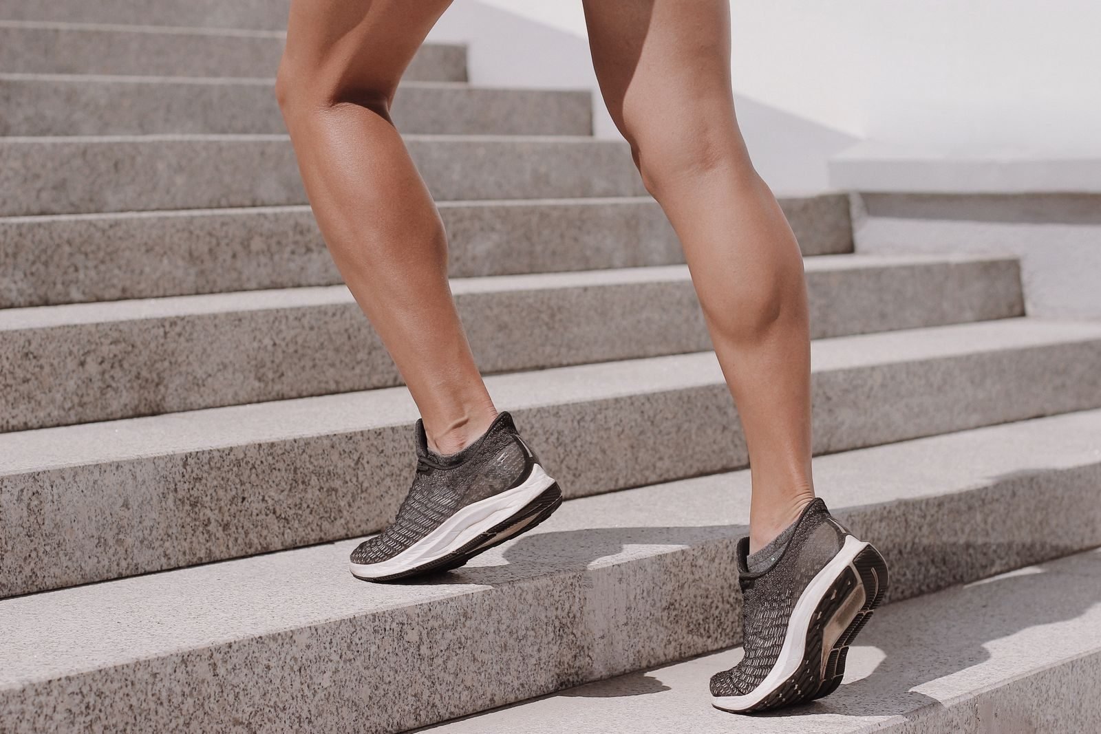 Legs of an athlete climbing stairs with defined calves, useful for Achilles tendinitis