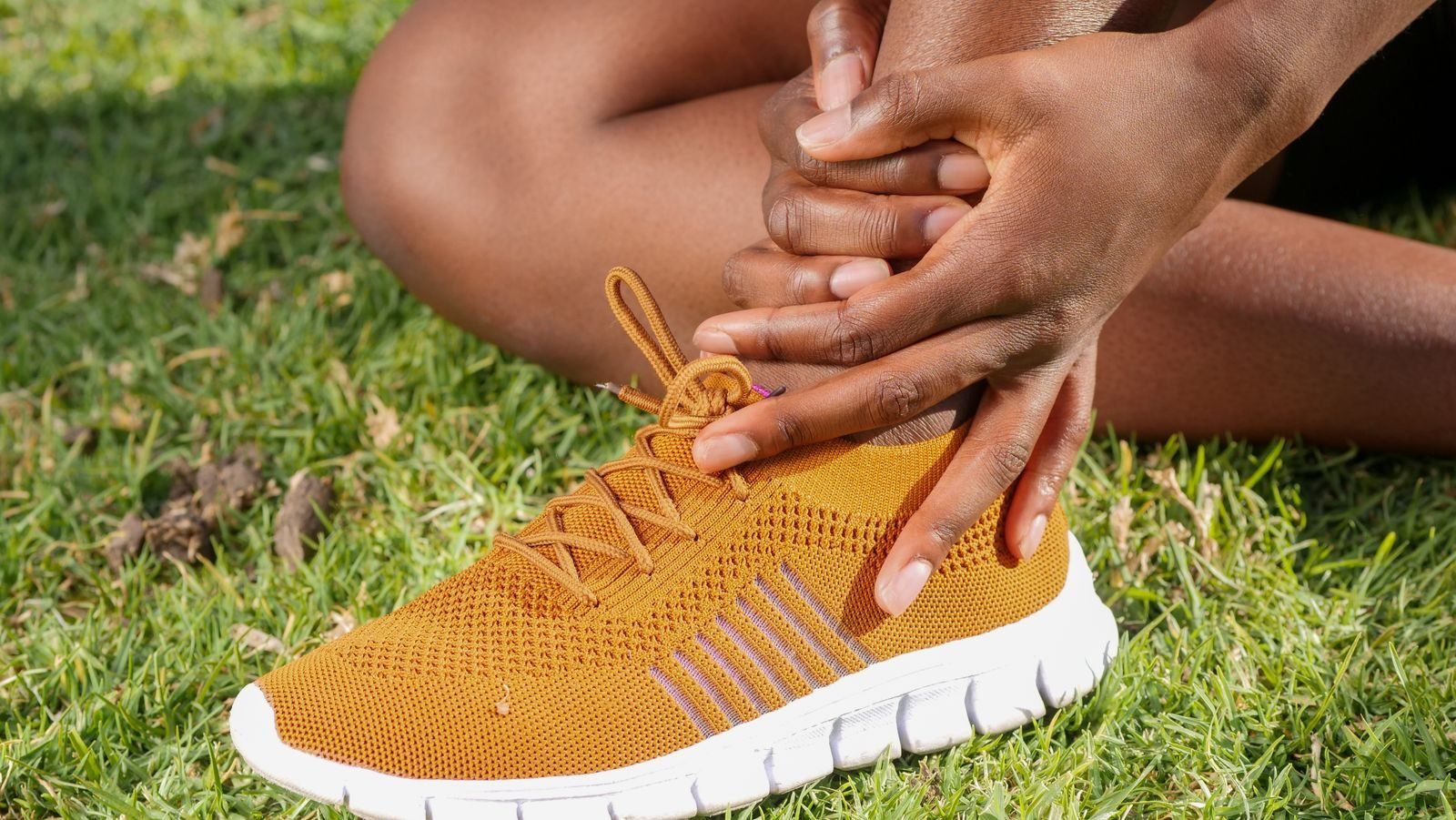 Athlete holding his ankle in a running shoe because of Achilles tendinitis pain