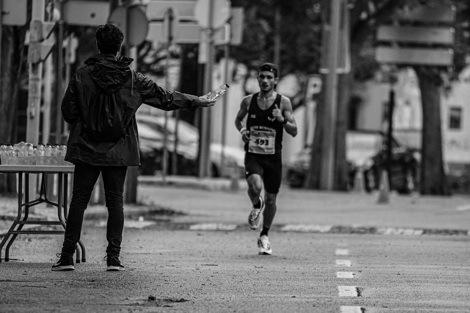 Runner taking water at an aid station to wash down his running gels