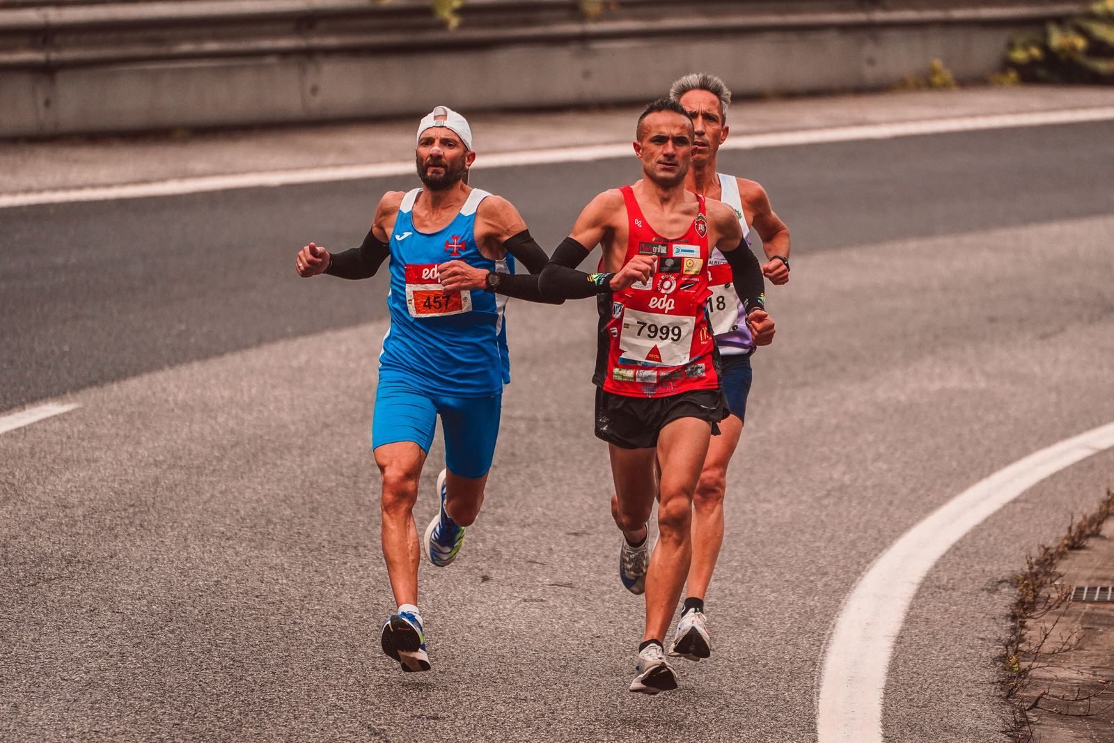 Tres corredores compitiendo en una carrera por una carretera de la ciudad