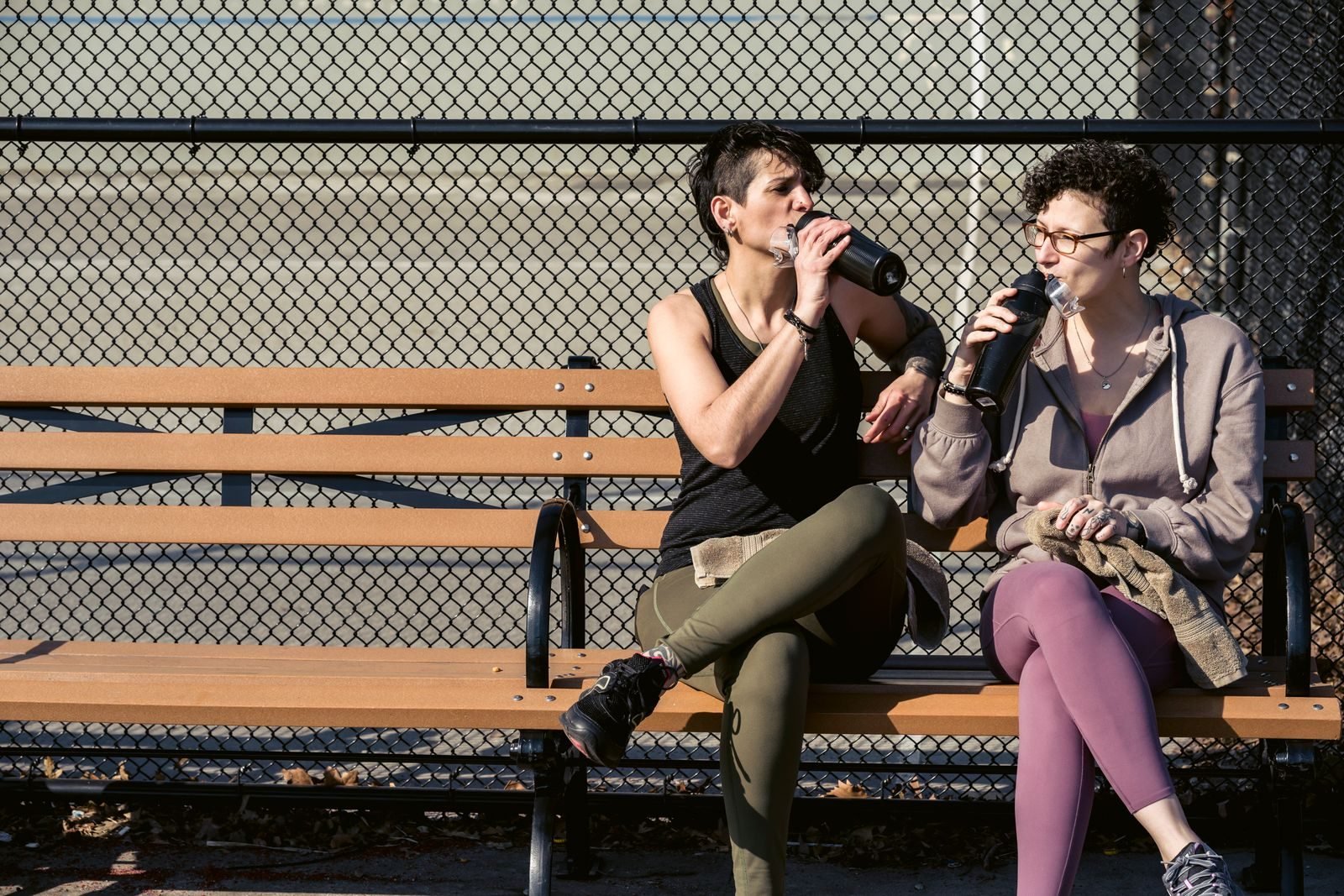 Friends resting on a bench and drinking water, part of marathon recovery
