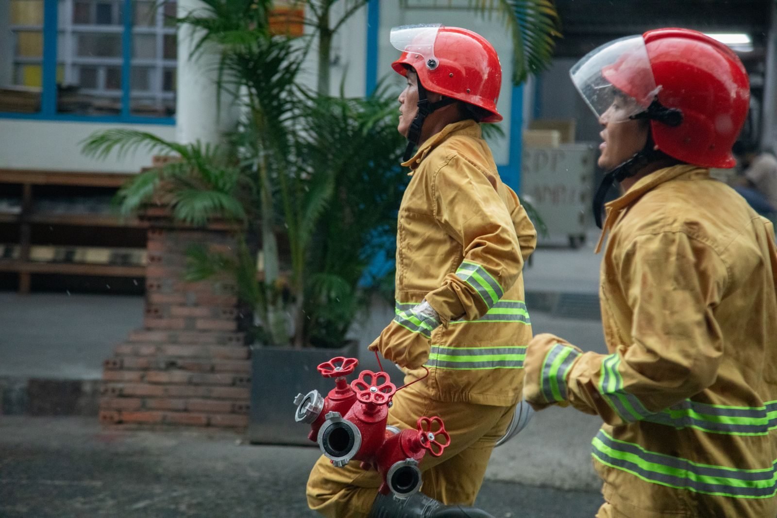 Dos bomberos corriendo con su equipo por la ciudad, en el espíritu de la Cursa de Bombers