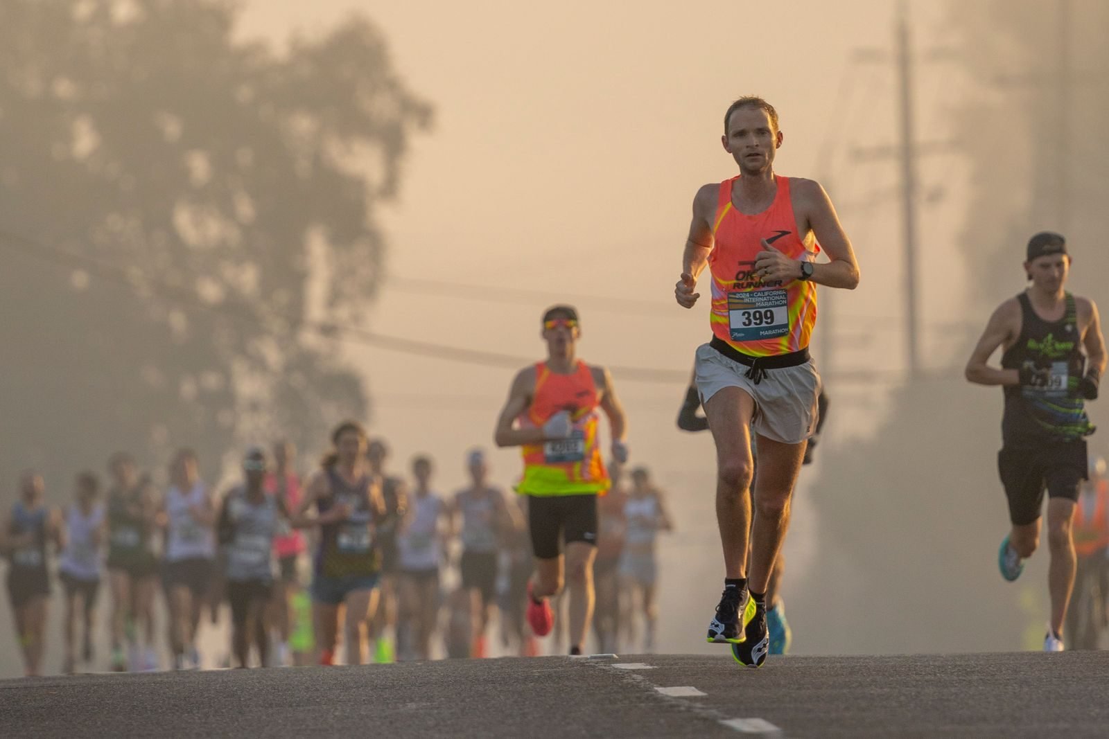 Corredor en cabeza de una maratón en una mañana con niebla