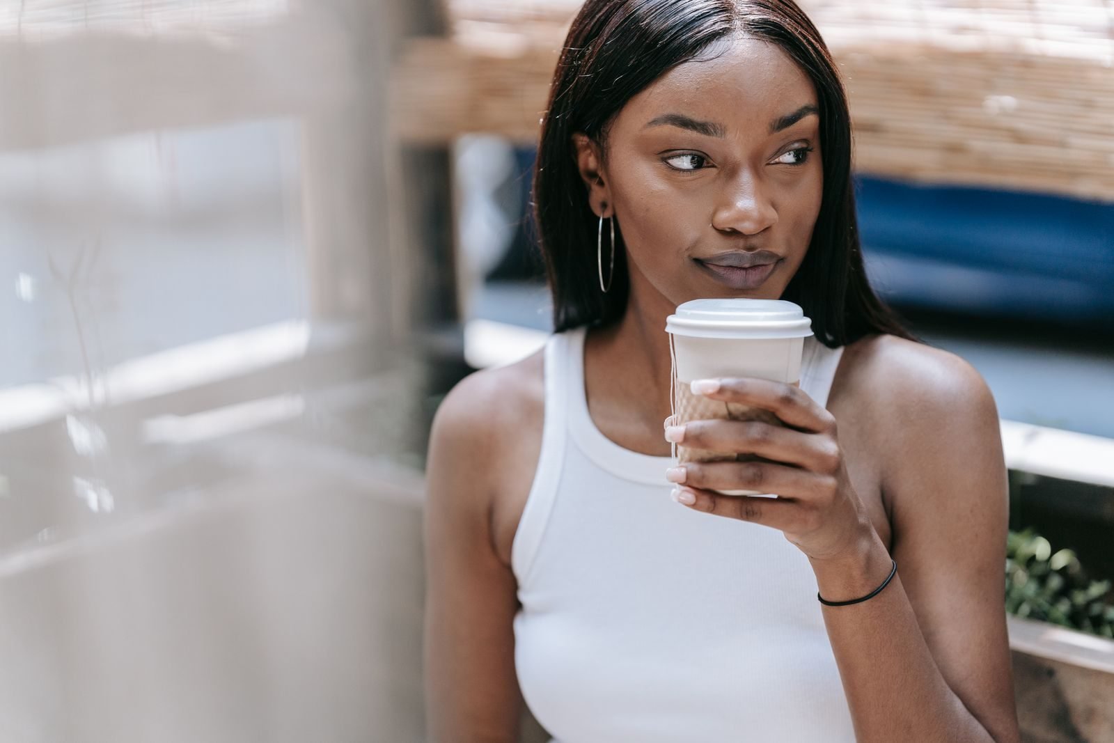 Woman in a tank top drinking a hot coffee outdoors