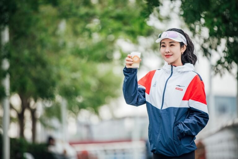Woman in sportswear holding a coffee in a park before running