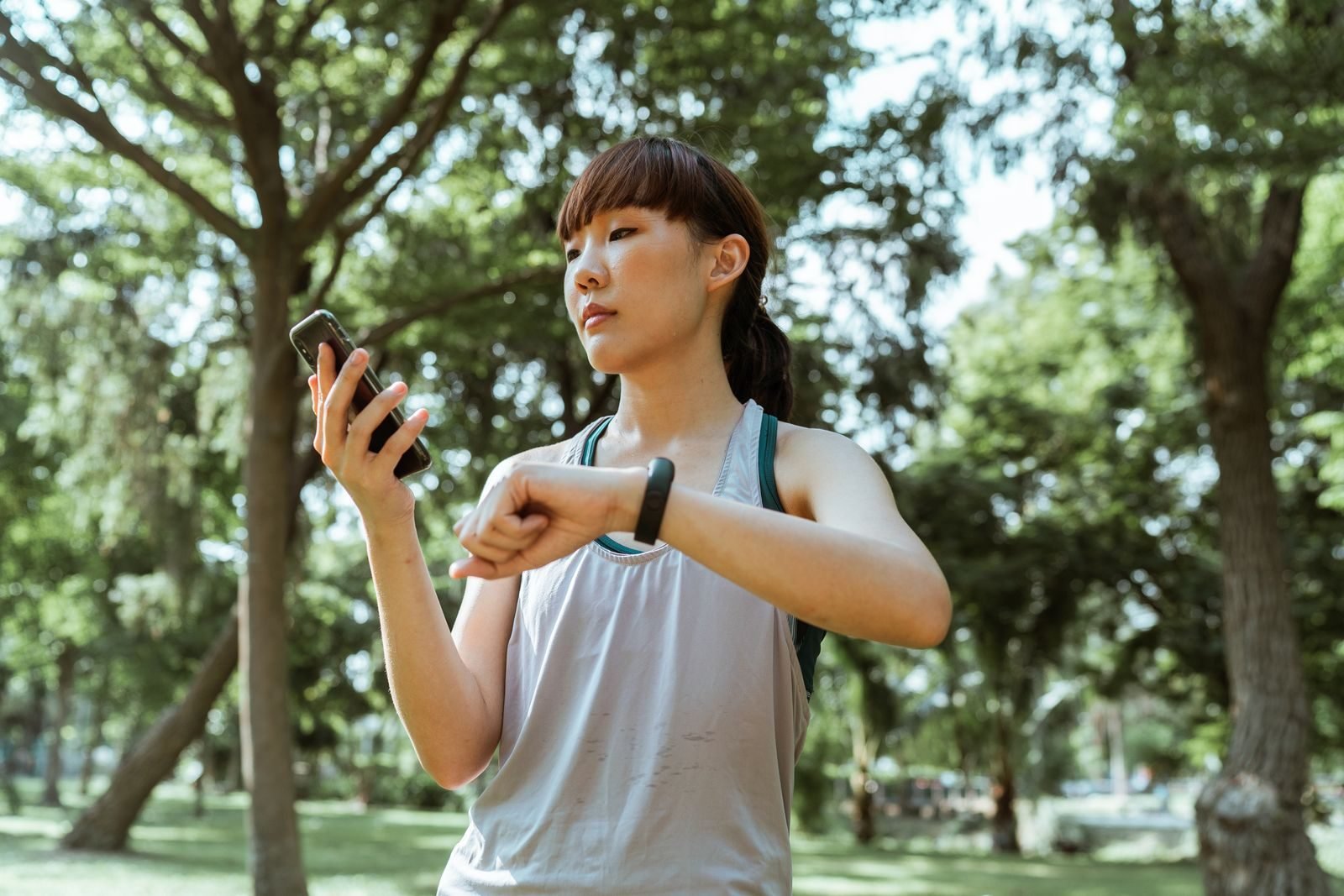 Corredora mirando el reloj y el móvil para usar la calculadora de ritmo antes de entrenar