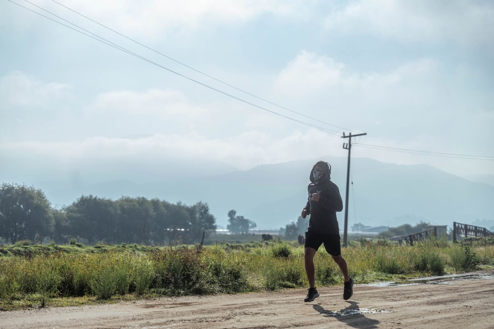Persona corriendo por un camino de tierra con montañas al fondo