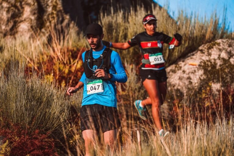 Two trail runners with bibs in tall grass, illustrative photo for Carenes del Cogulló 2026