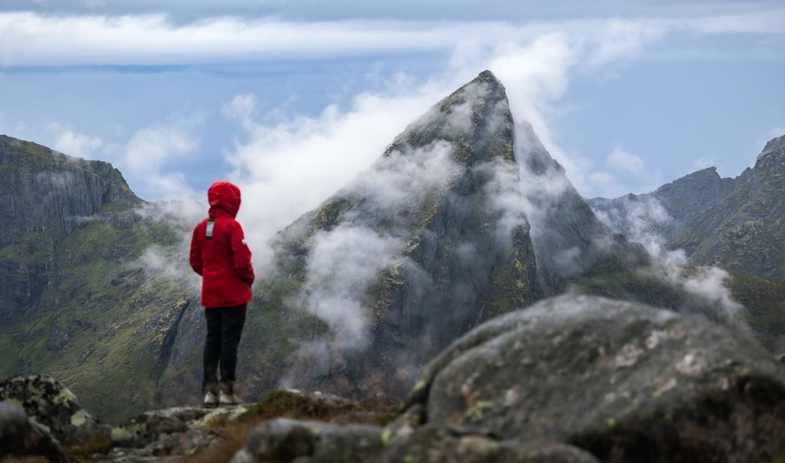 Mujer con chaqueta roja caminando por la montaña con niebla