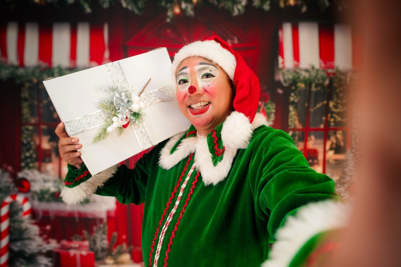 Person dressed as an elf holding a Christmas gift box