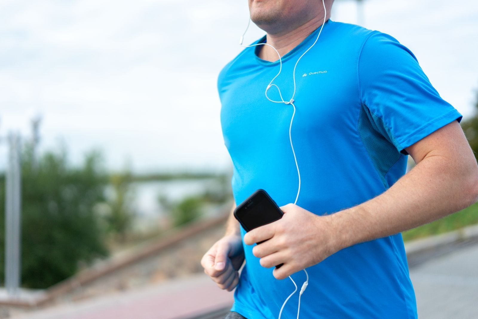 Corredor con auriculares y el móvil en la mano, regalos para runners hombre tecnológicos