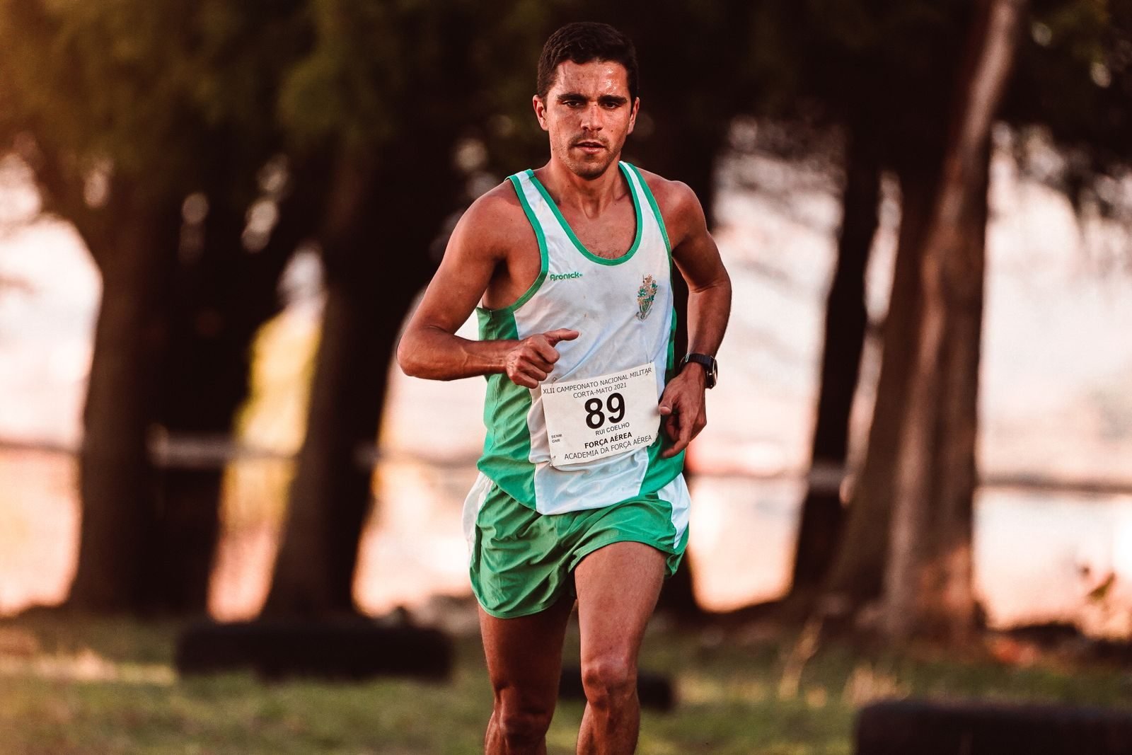 Corredor con dorsal en una carrera popular entre árboles