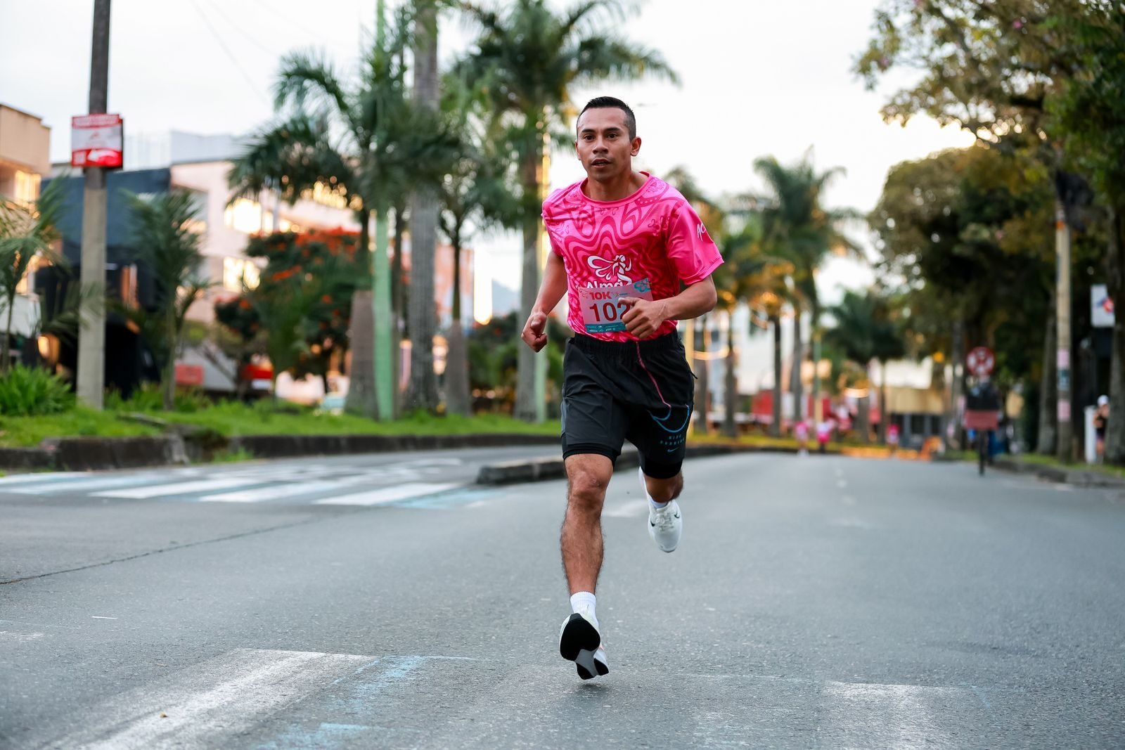 Corredor con camiseta rosa en una carrera urbana