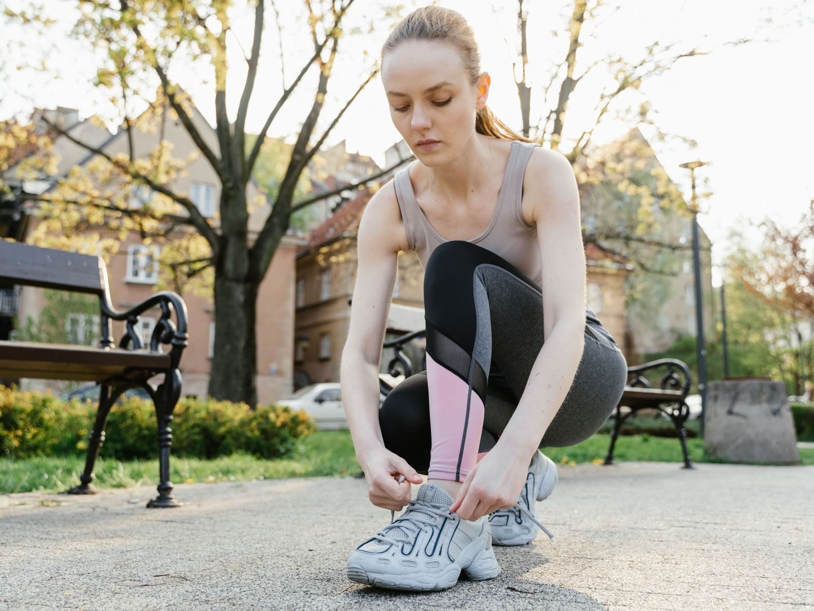 Corredora atándose las zapatillas en un parque antes de entrenar
