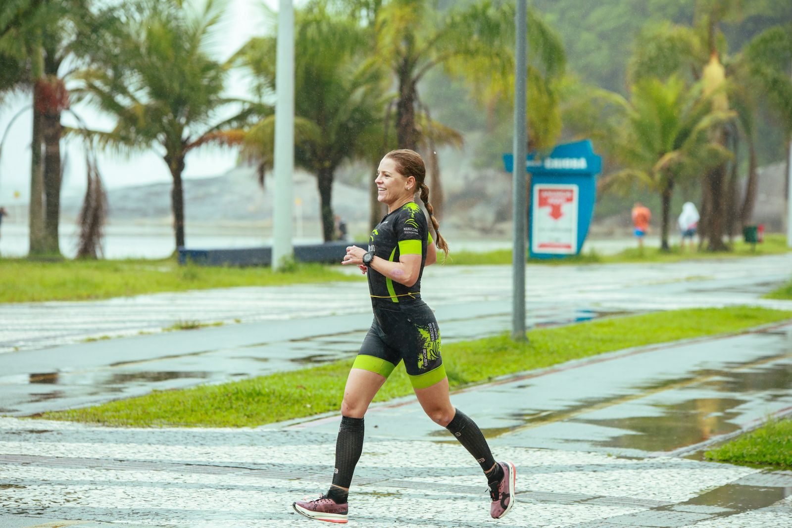 Mujer corriendo por un camino mojado entre palmeras