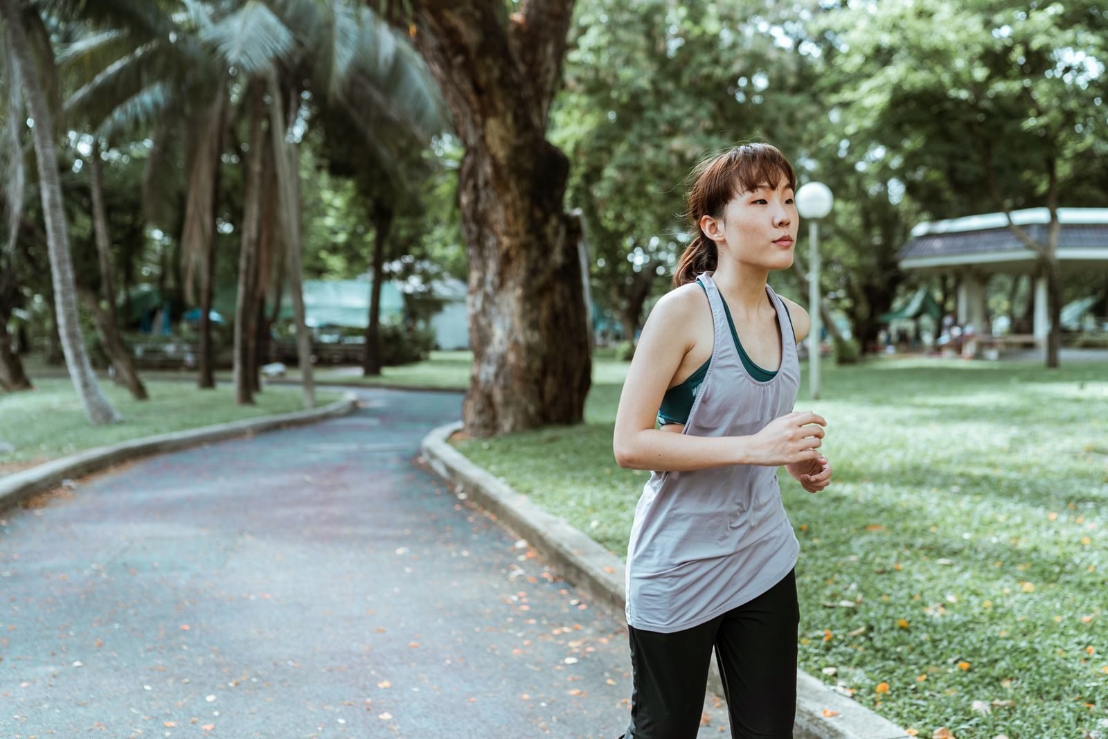 Corredora entrenando al aire libre por una carretera con hojas