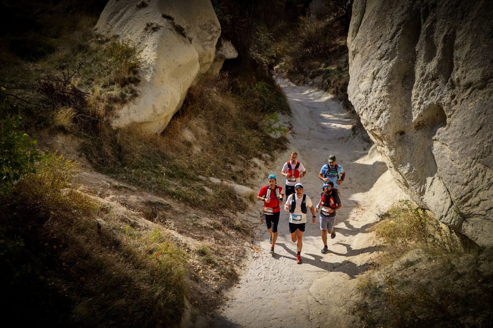 Grupo de corredores bajando por un sendero entre rocas en una carrera de montaña