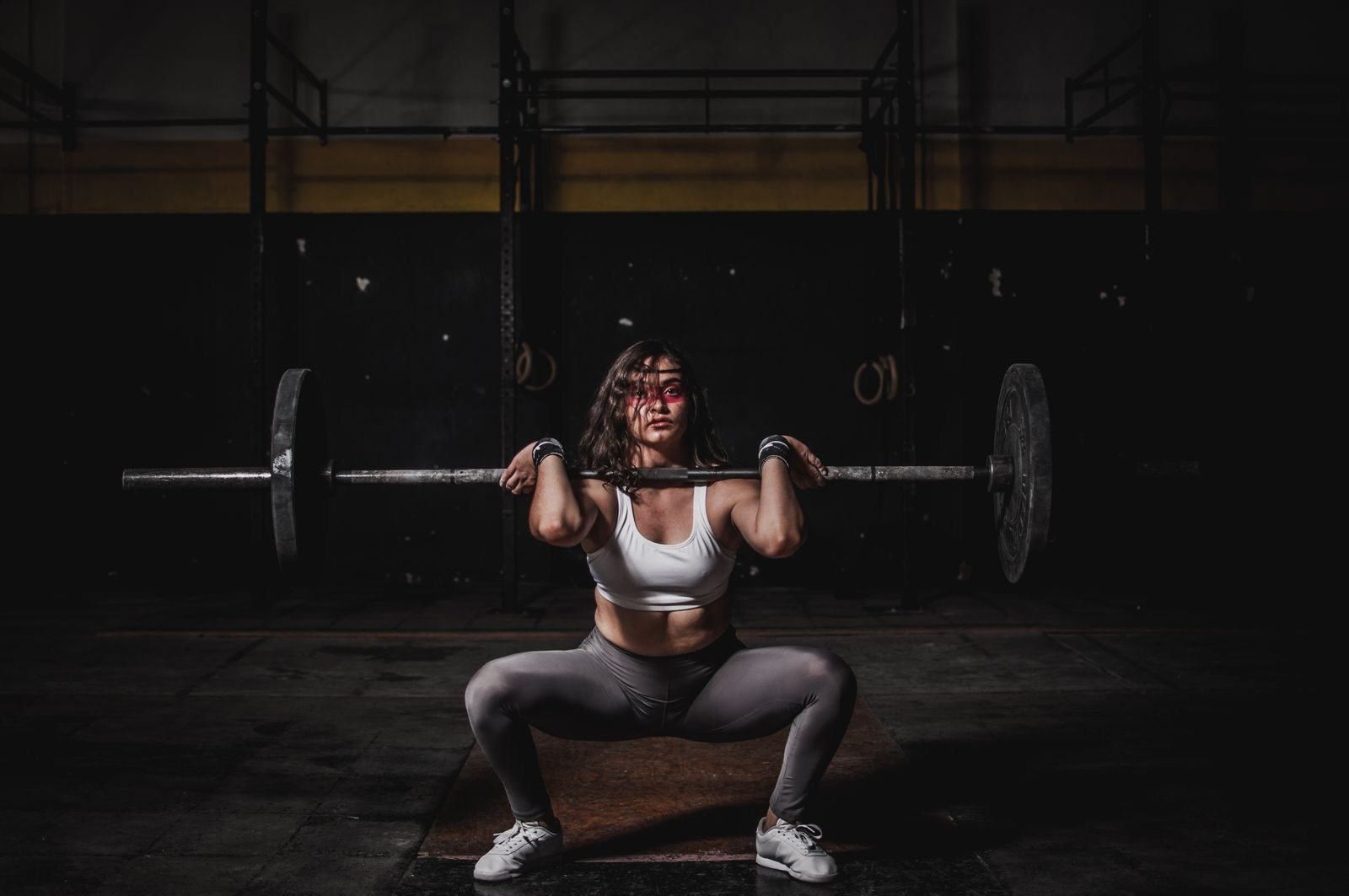 Mujer haciendo sentadilla con barra en el gimnasio para ganar fuerza