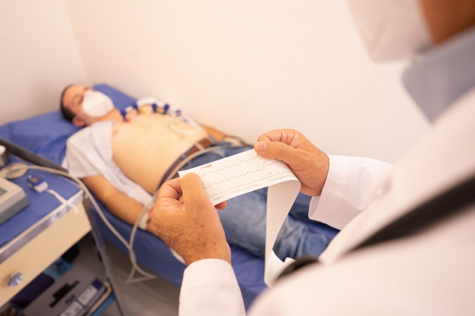 Doctor reviewing an ECG printout next to a patient lying down