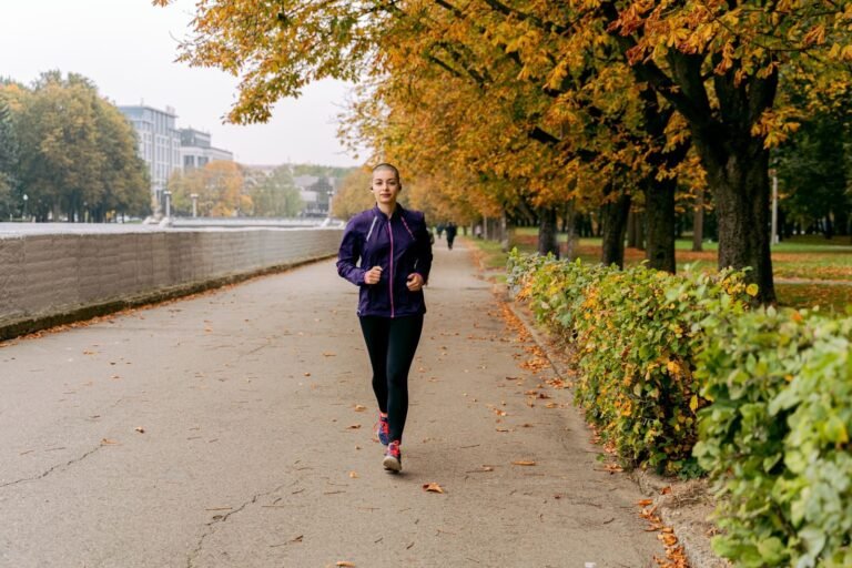 Mujer corriendo por un paseo con árboles en otoño