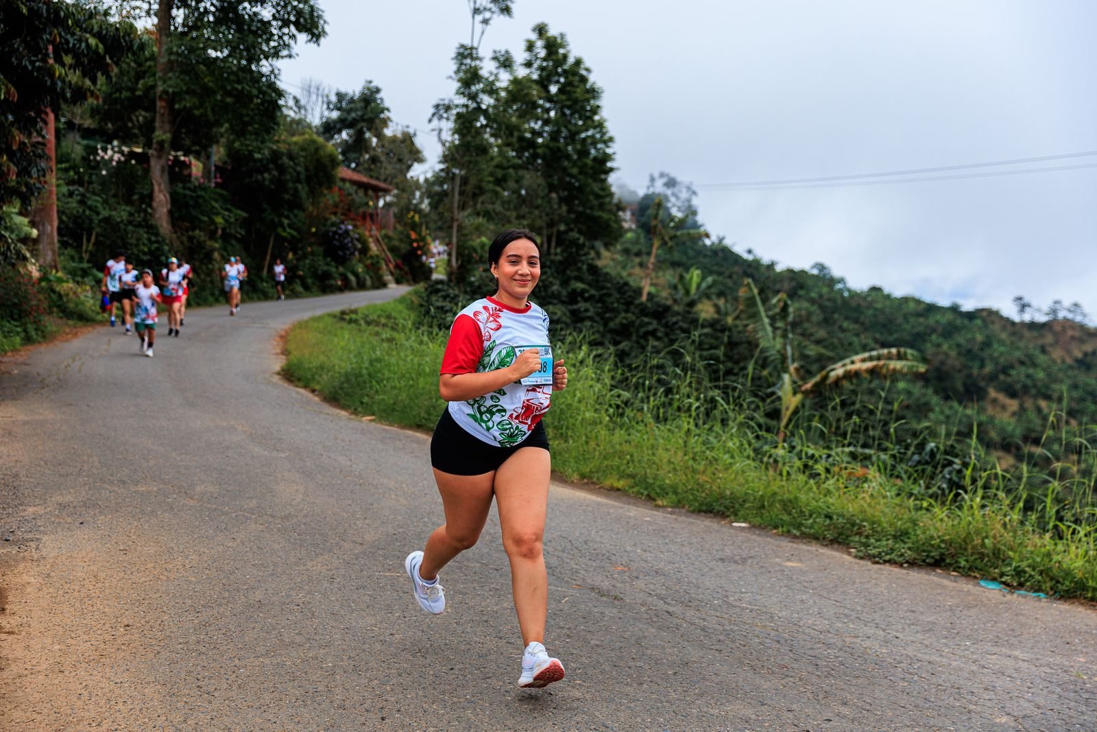 Mujer corriendo cuesta arriba por una carretera rural durante una carrera
