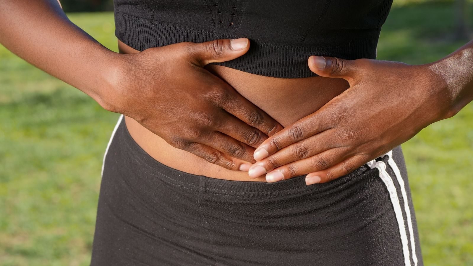 Persona al aire libre sujetándose el abdomen por molestias digestivas