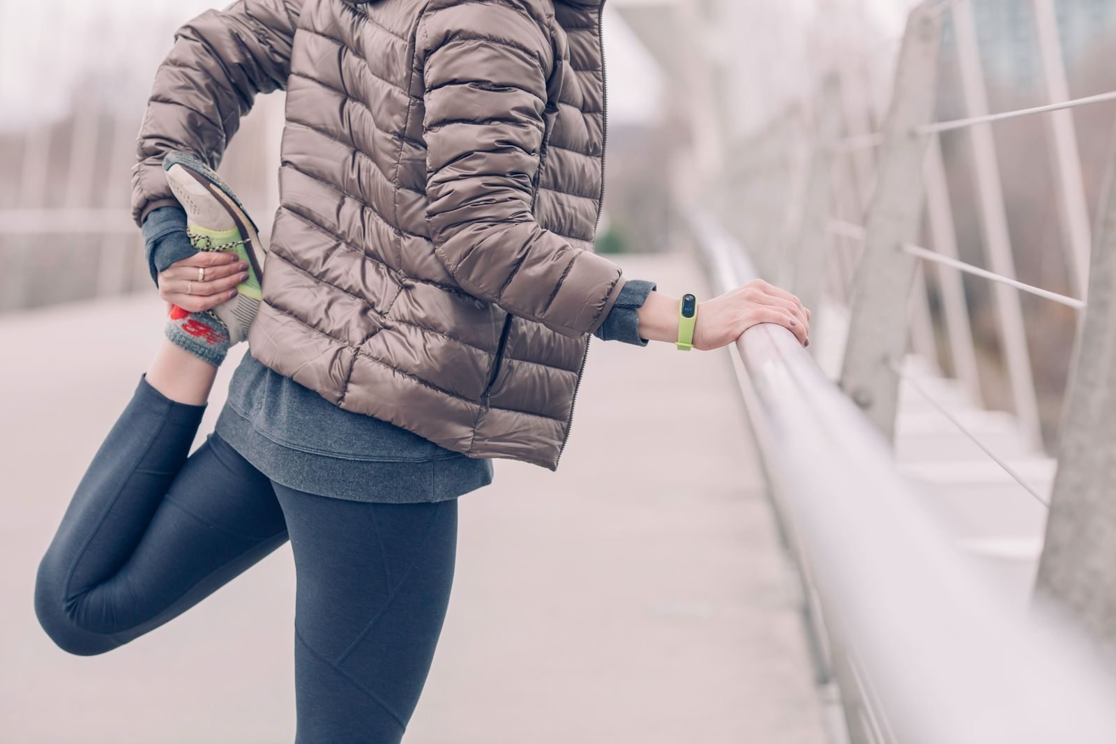 Mujer estirando las piernas en un puente antes de salir a correr