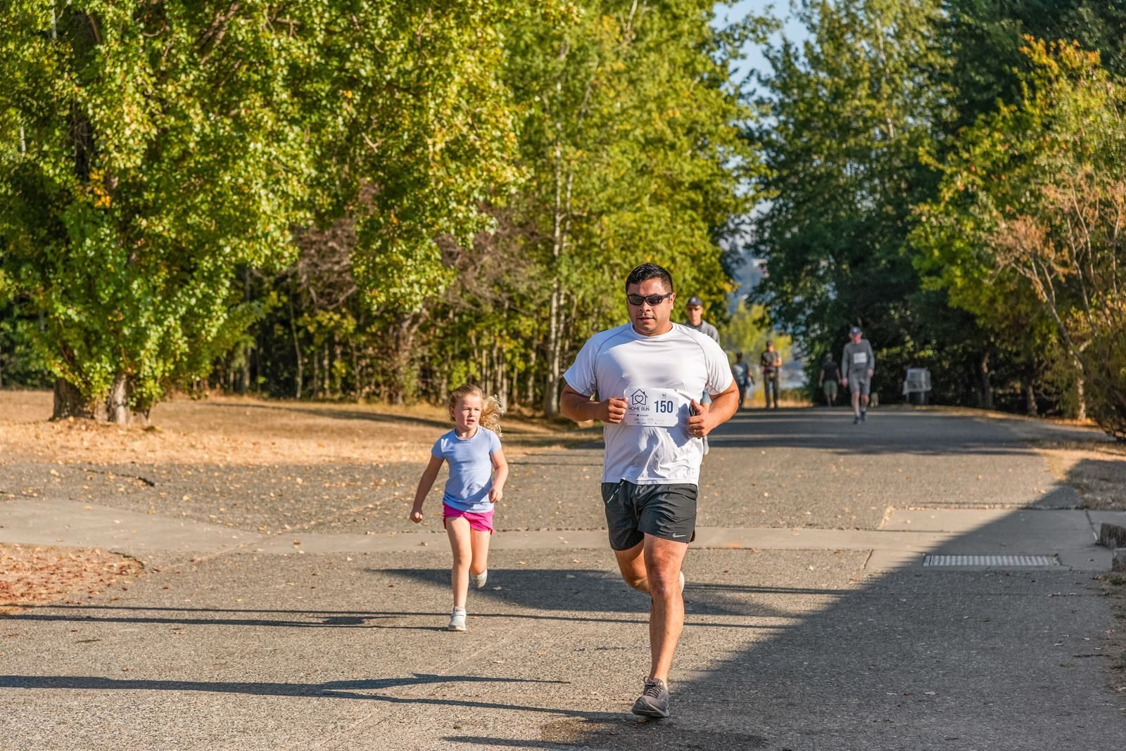 Hombre y niña corriendo juntos por un parque soleado