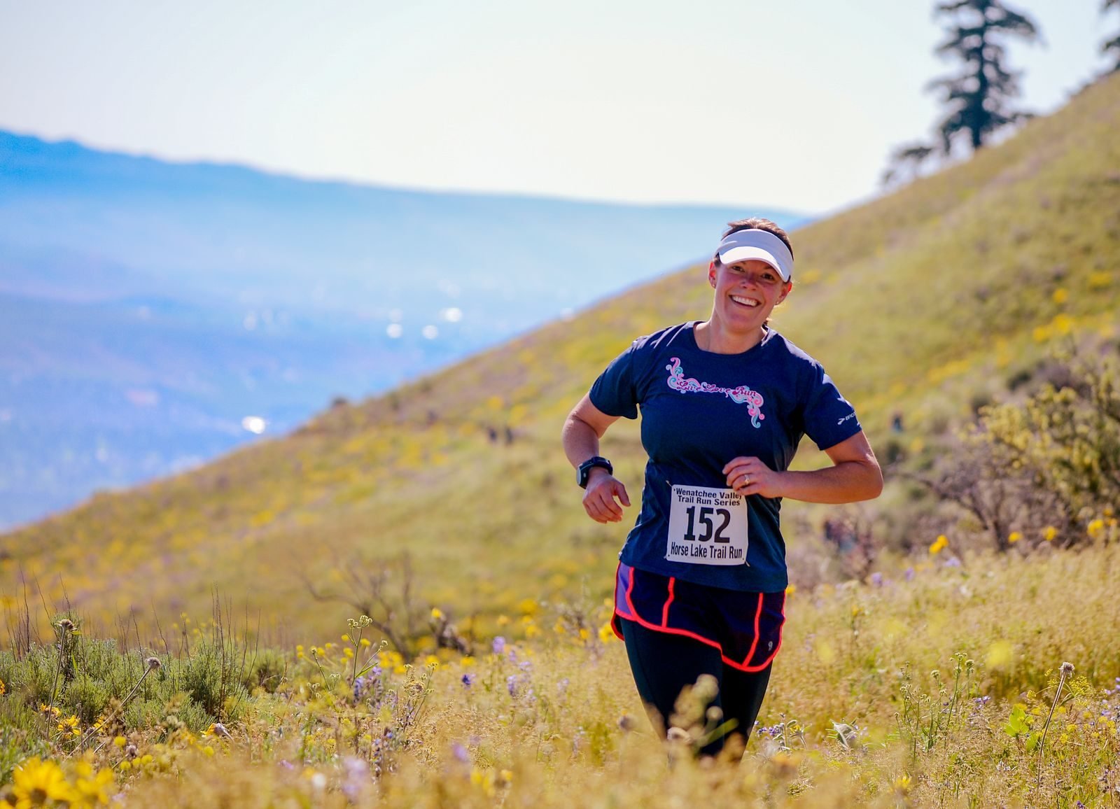 Female runner with a bib in her first trail race on a mountain slope