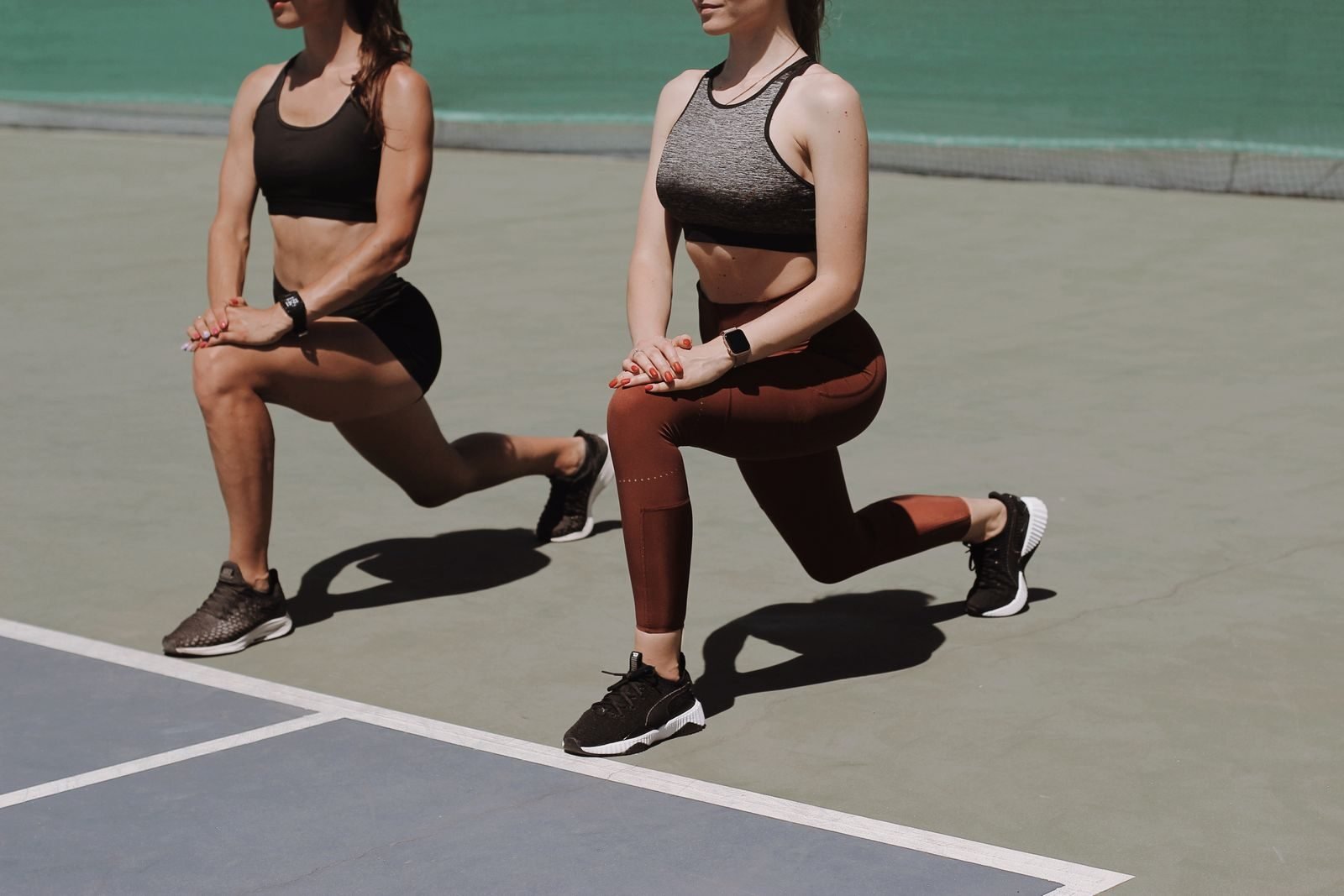 Dos mujeres haciendo zancadas en una pista deportiva como parte de su fuerza para corredores