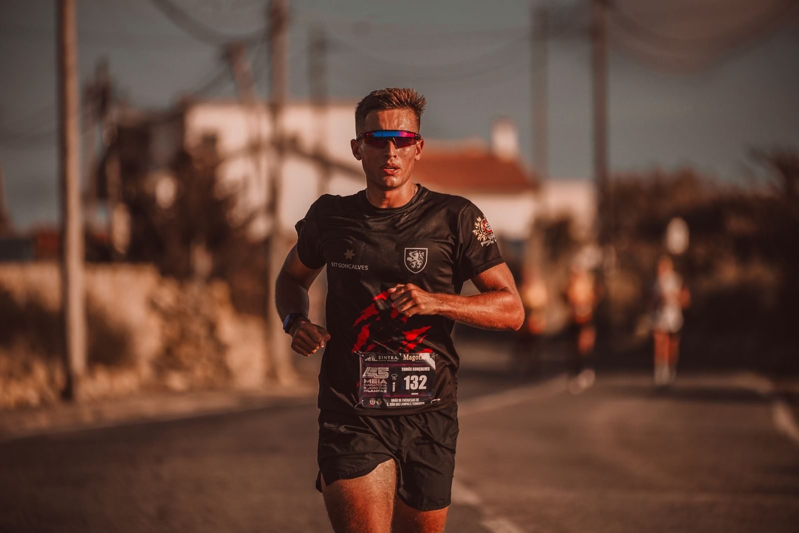 Corredor con gafas de sol durante un maratón urbano en el que toma geles para correr