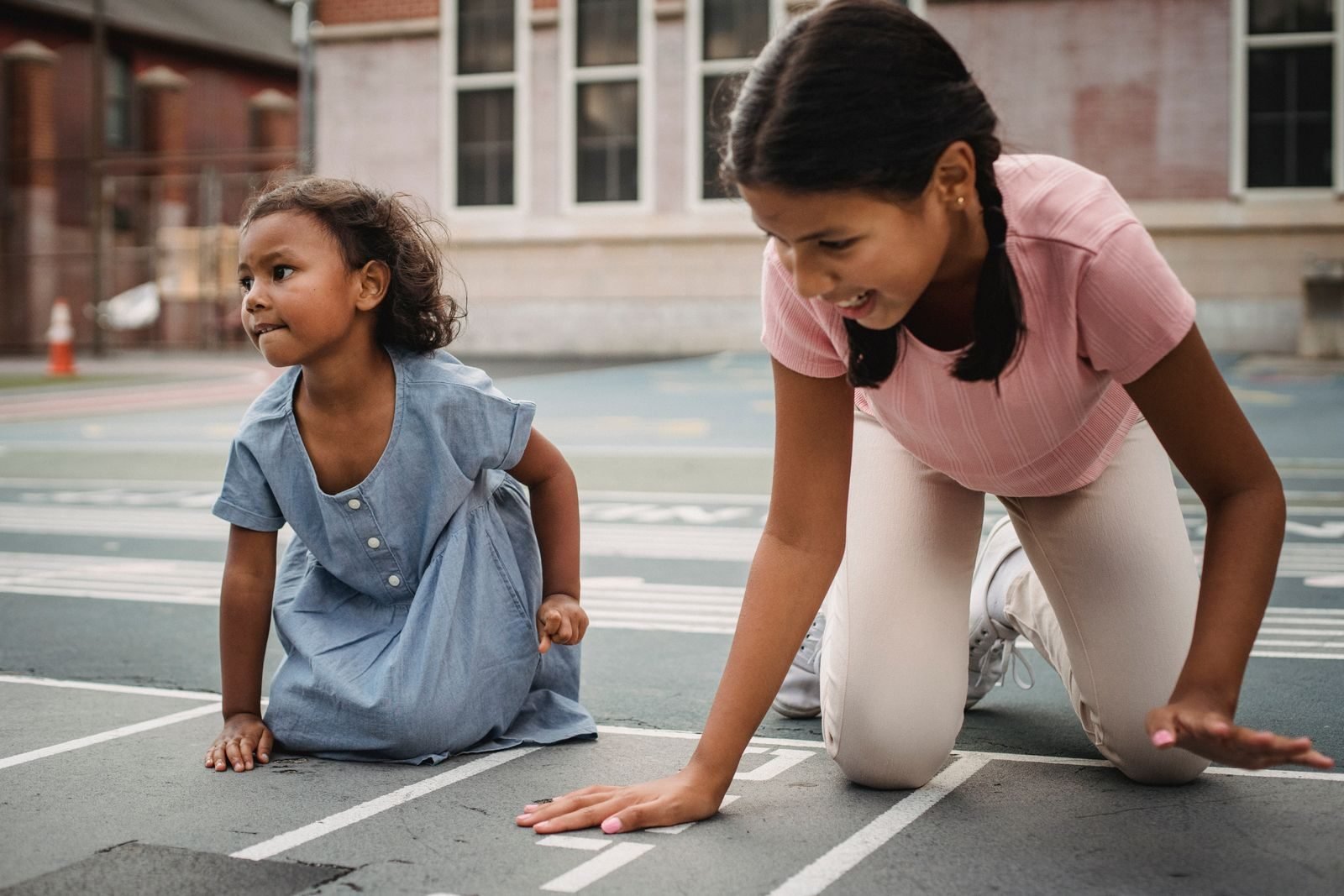 Two girls playing on a school playground track, running gifts for kids