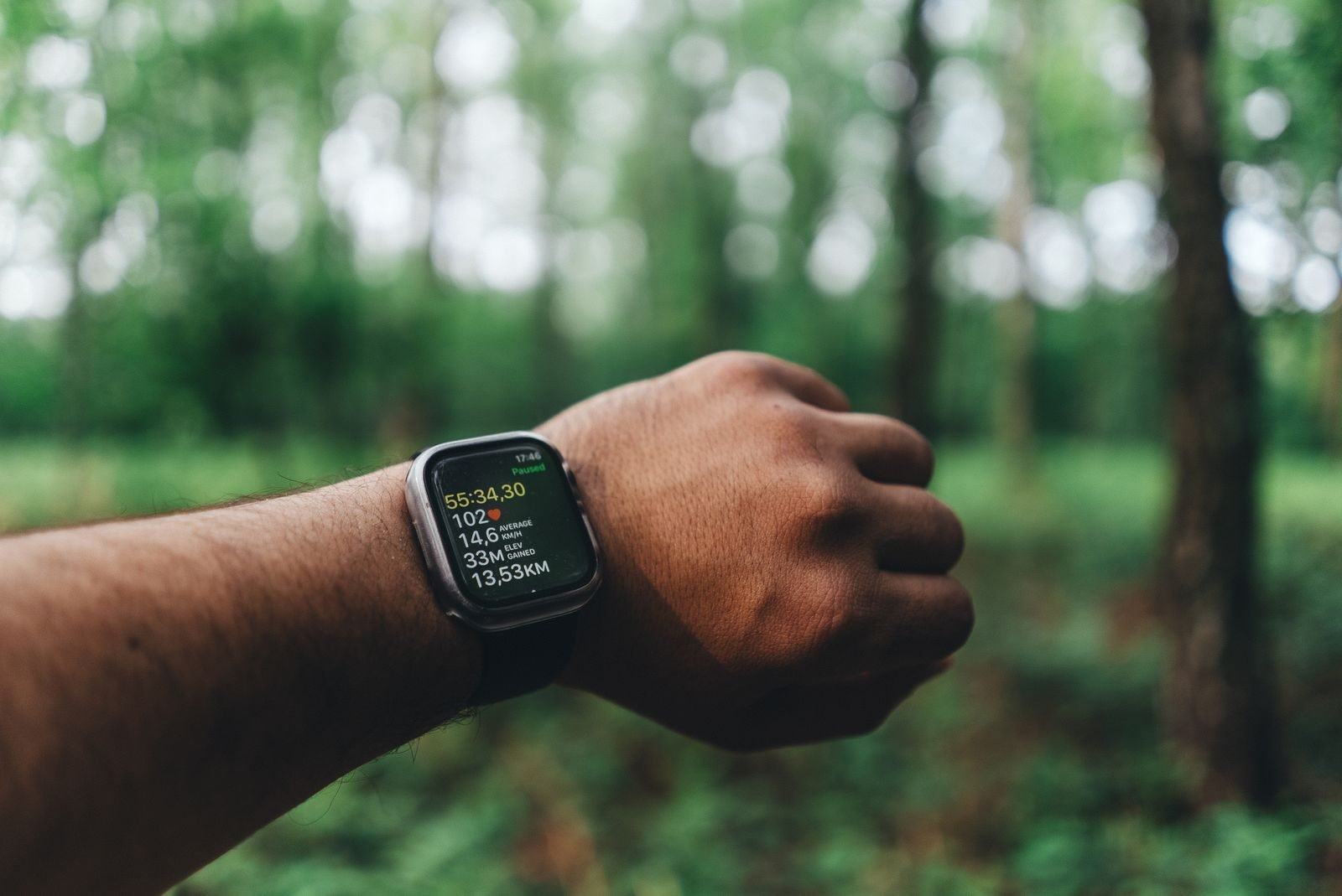 GPS running watch on a wrist showing training data with a forest in the background