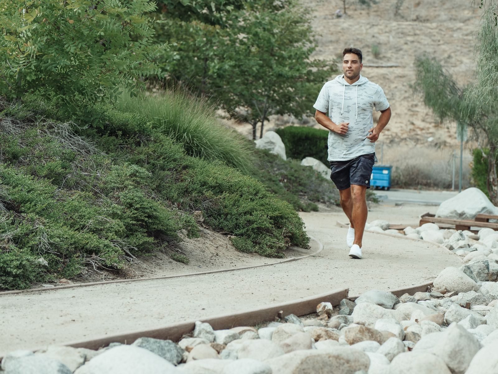 Man running on a green trail with rocks