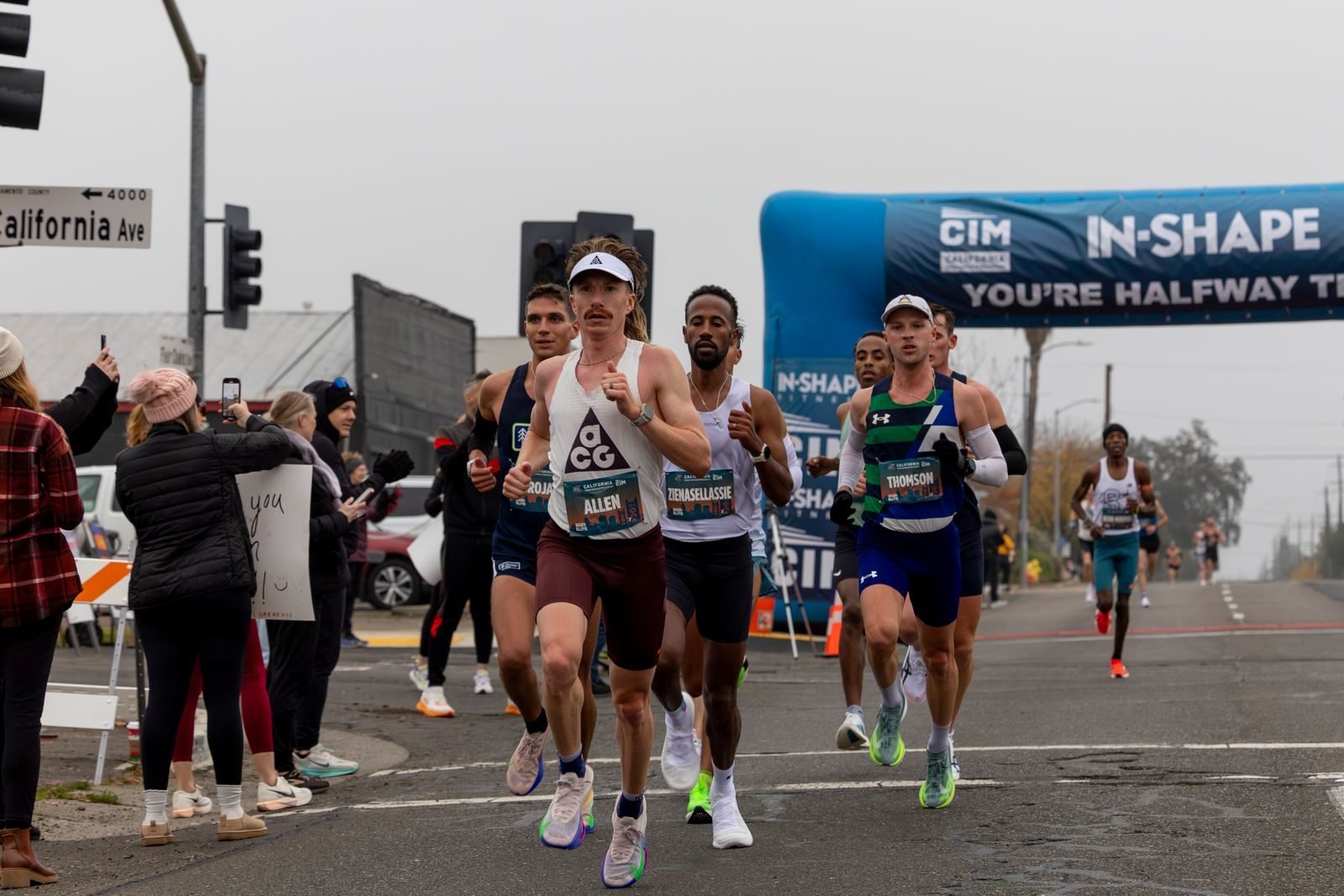 Group of runners approaching the finish of a half marathon after following their half marathon training plan