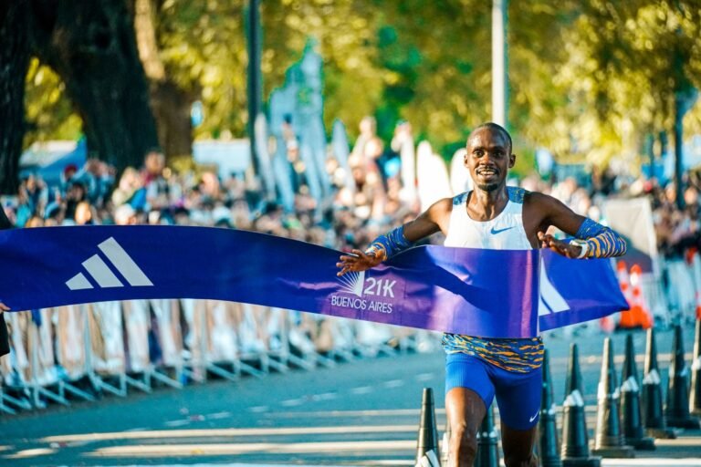 Runner crossing the finish line of a half marathon with the 21K tape