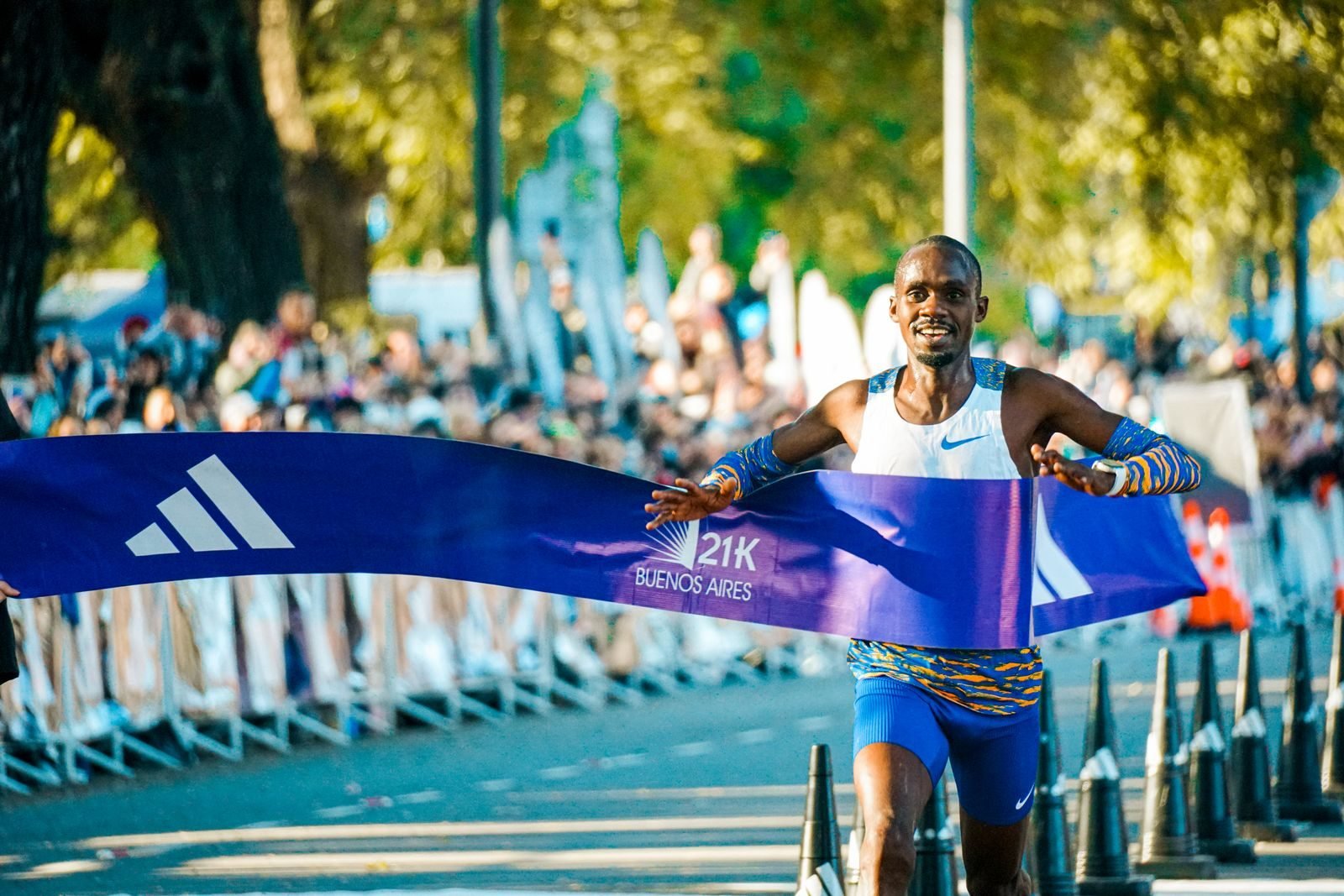 Runner crossing the finish line of a half marathon with the 21K tape