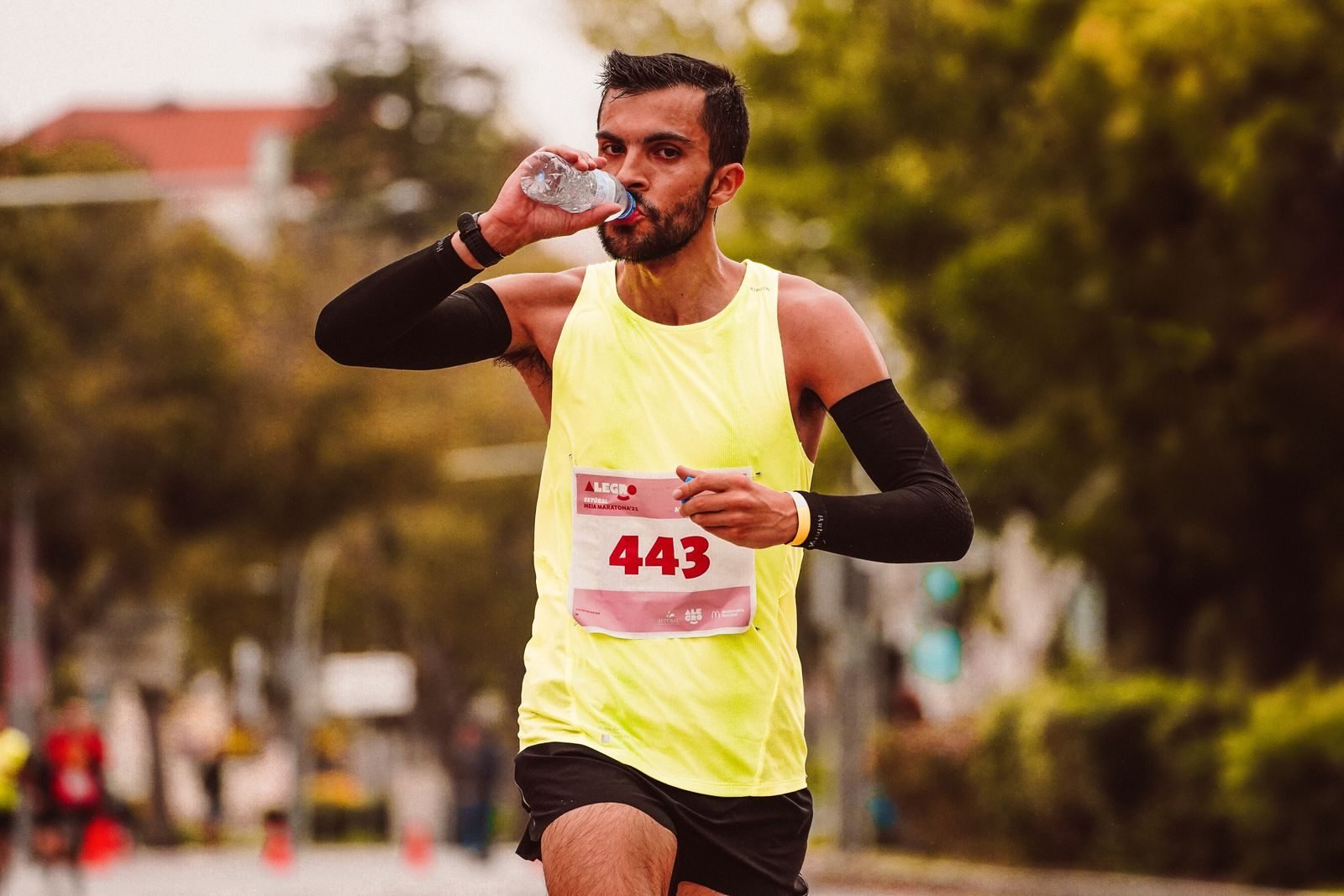 Corredor bebiendo agua de una botella durante una carrera en ciudad