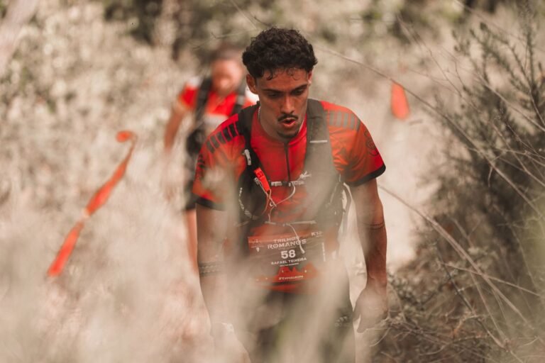 Trail runner with a bib climbing through vegetation, illustrative photo for Imperial Tarraco Trail 2026