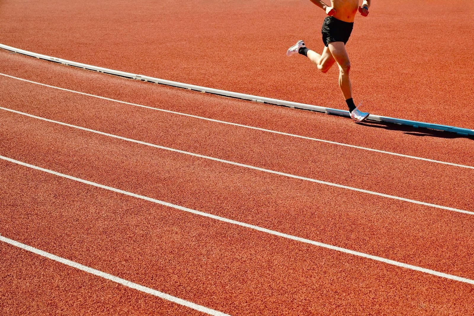 Athlete running intervals on a red running track
