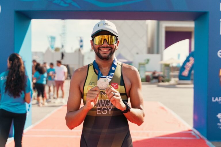 Smiling runner showing his medal after finishing a marathon