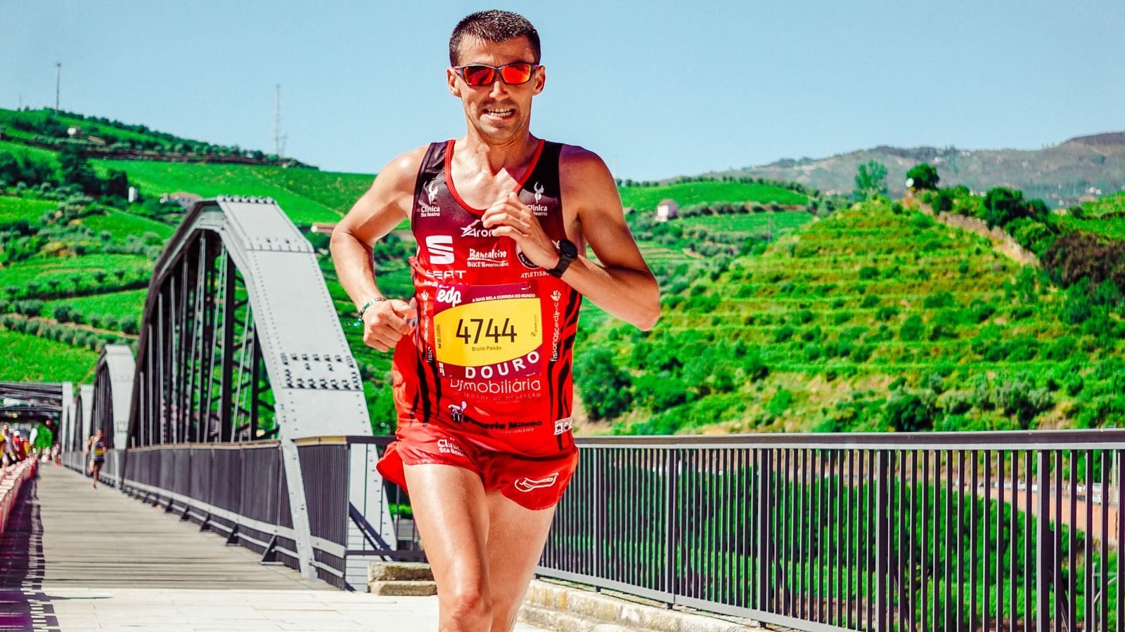 Marathon runner in red crossing a bridge during an endurance exercise race