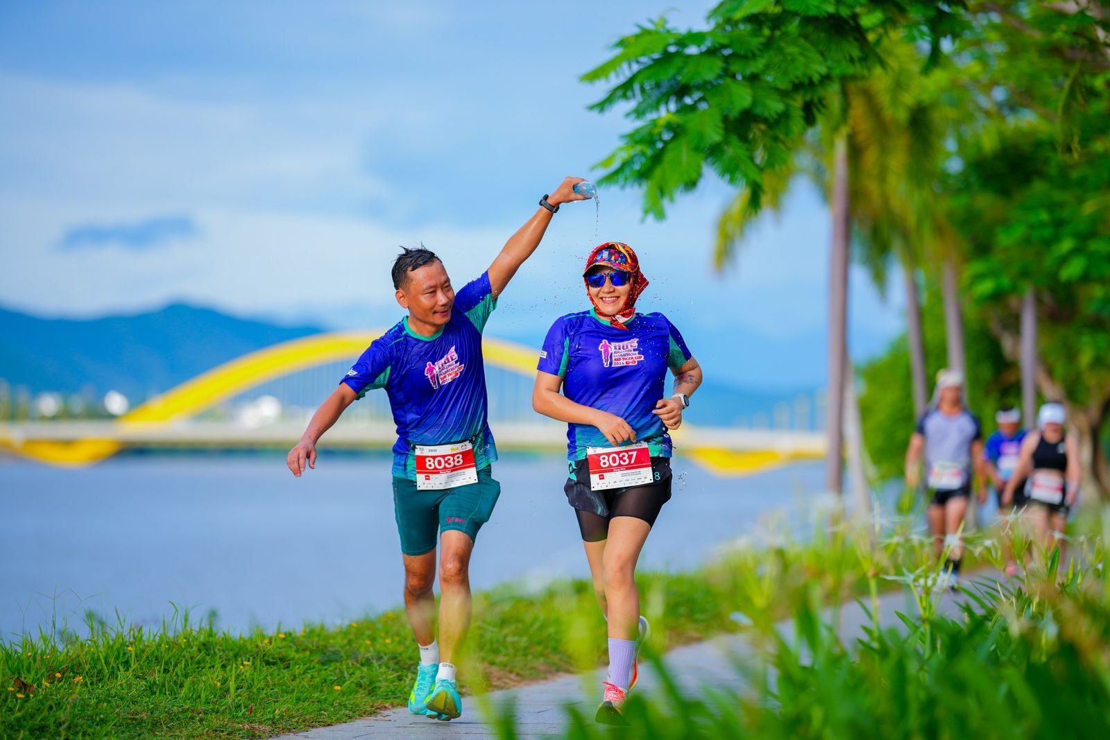 Two smiling runners in a marathon along a river