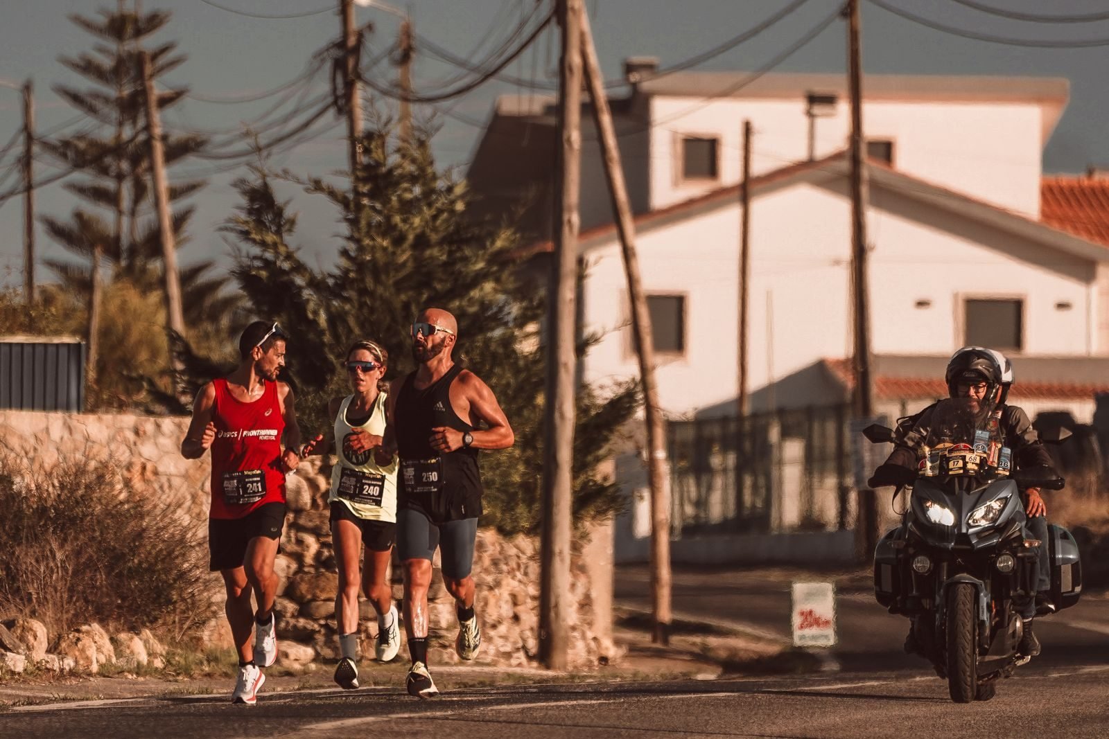 Corredores de un maratón urbano pasando junto a una moto