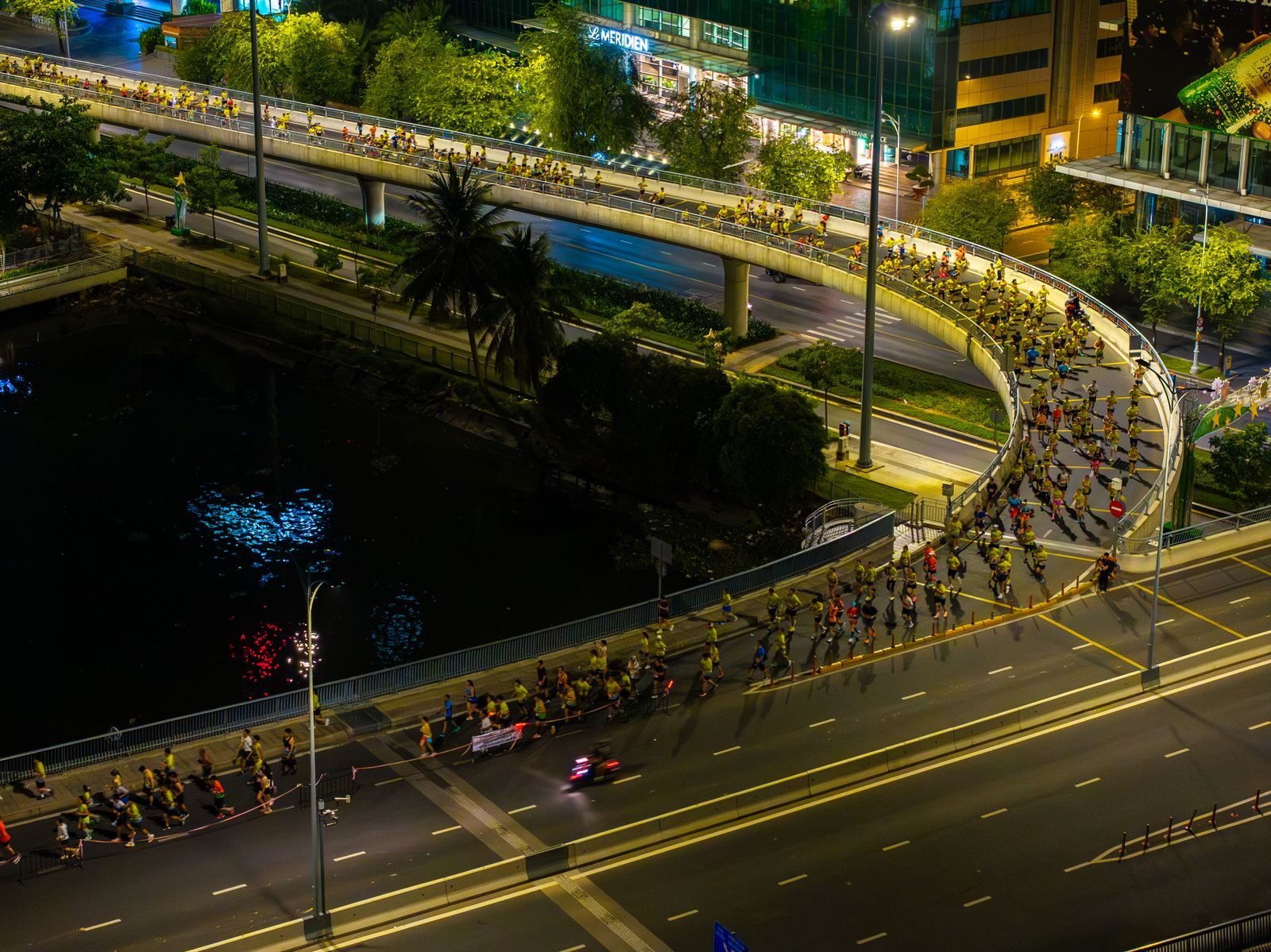 Vista aérea de un maratón nocturno cruzando un paso elevado
