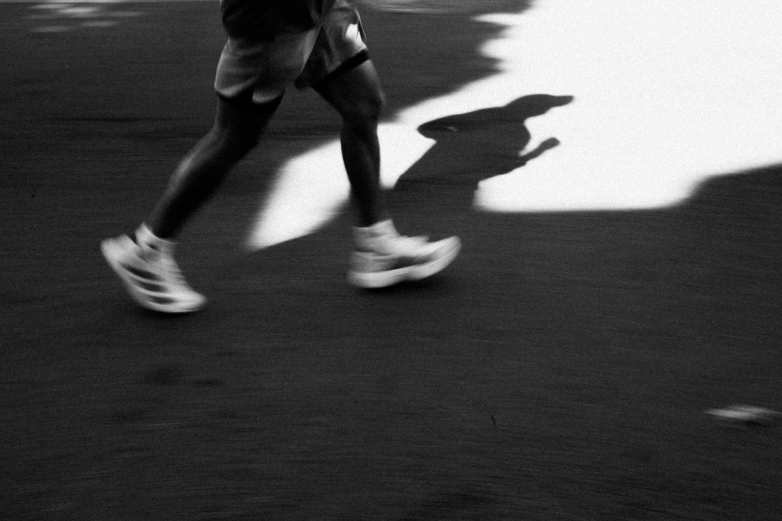 Shadow of a runner cast on the tarmac in black and white