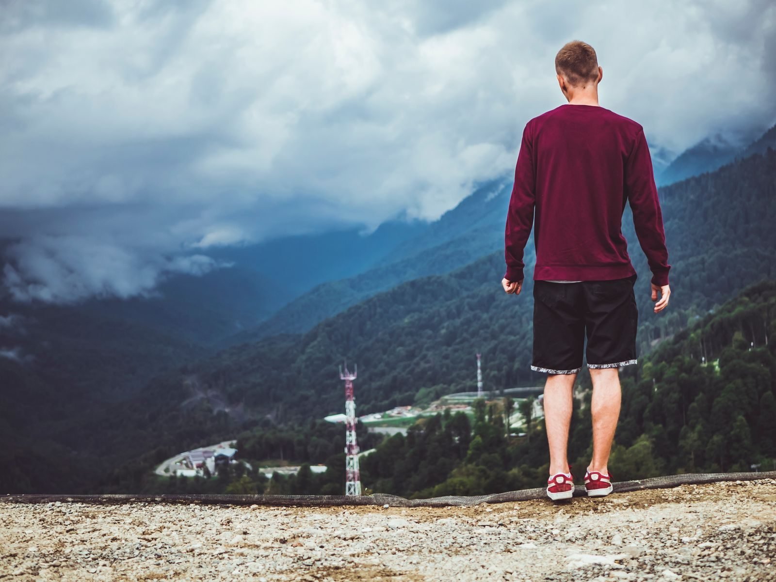 Hombre en la cima de una montaña mirando un valle entre nubes