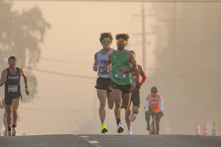 Grupo de corredores de maratón al amanecer controlando el ritmo para hacer un negative split